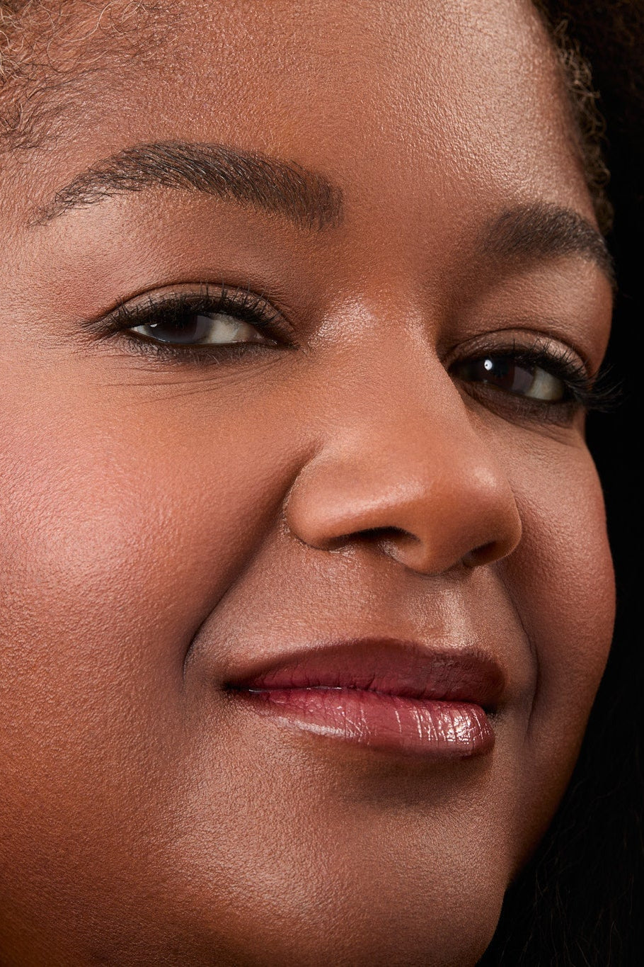 Close-up of a woman's face with a neutral expression wearing dark brown eyeliner.
