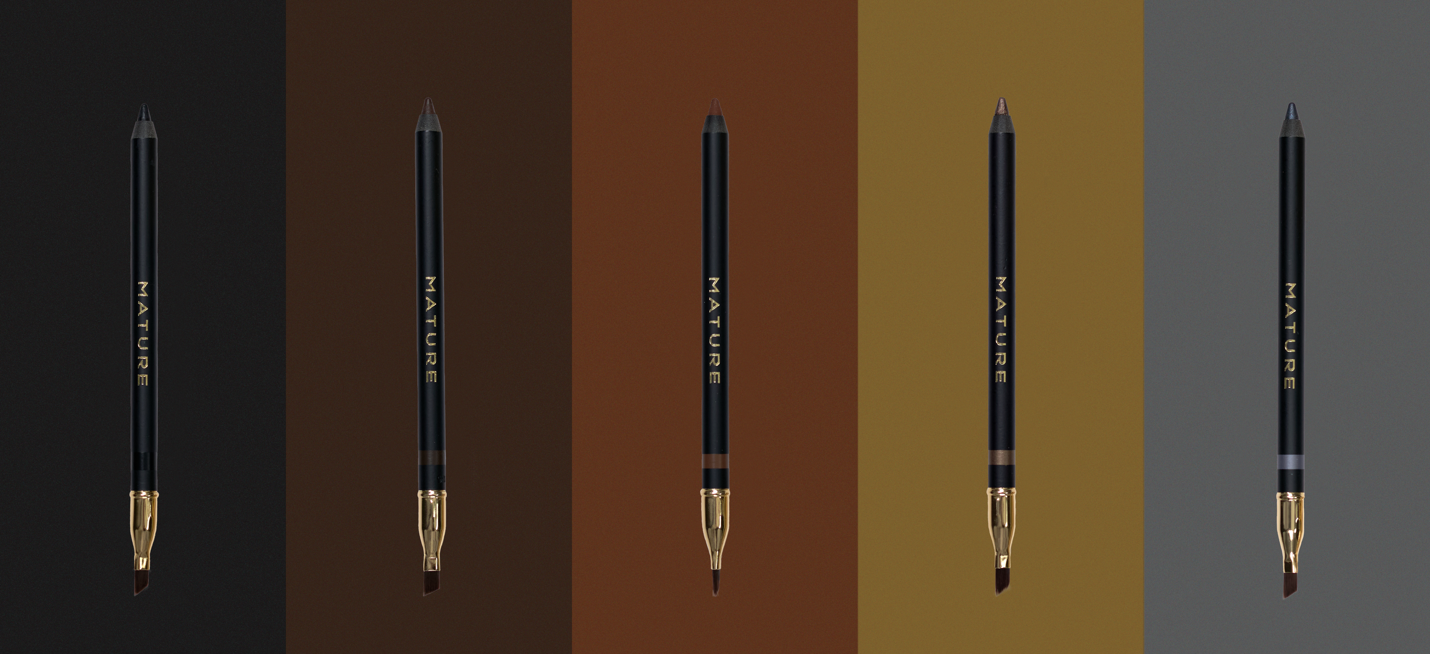 Set of five makeup pencils with gold accents on a gradient background. Black, Dark Brown, Chocolate Brown, Champagne Bronze, Steel Gray from left to right.