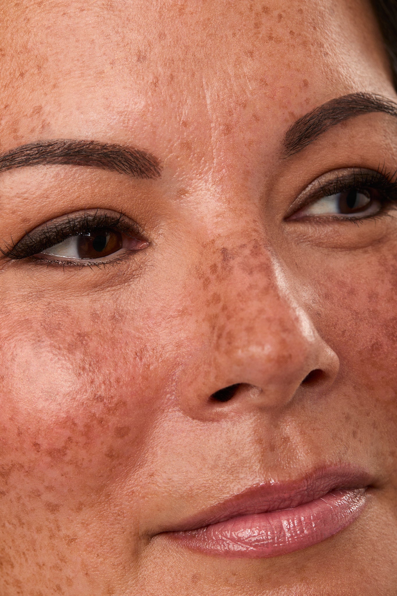 Close-up of a woman's face with freckles and brown eyes.