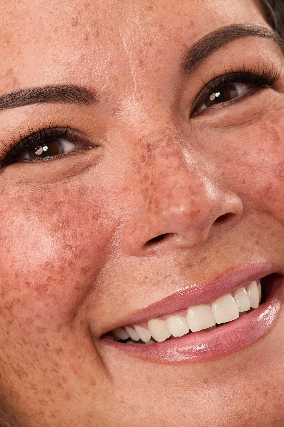 Close-up of a woman's face with a smile, showing teeth wearing Dark Brown eyeliner.